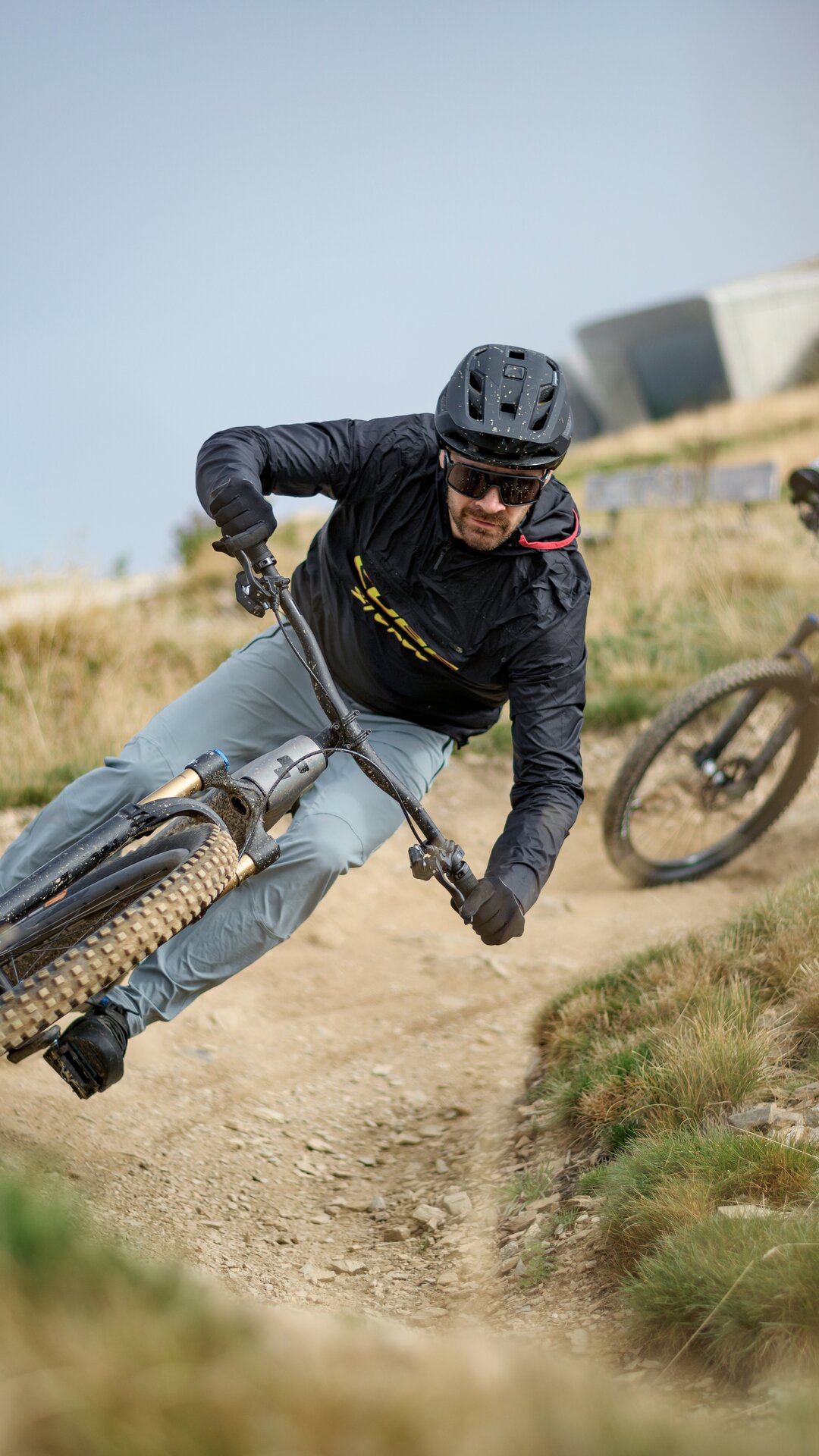 Zwei Mountainbiker nehmen eine enge Kurve auf einem steinigen Trail durch offenes Gelände. | © Cube Bikes