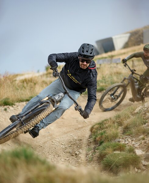 Zwei Mountainbiker nehmen eine enge Kurve auf einem steinigen Trail durch offenes Gelände. | © Cube Bikes
