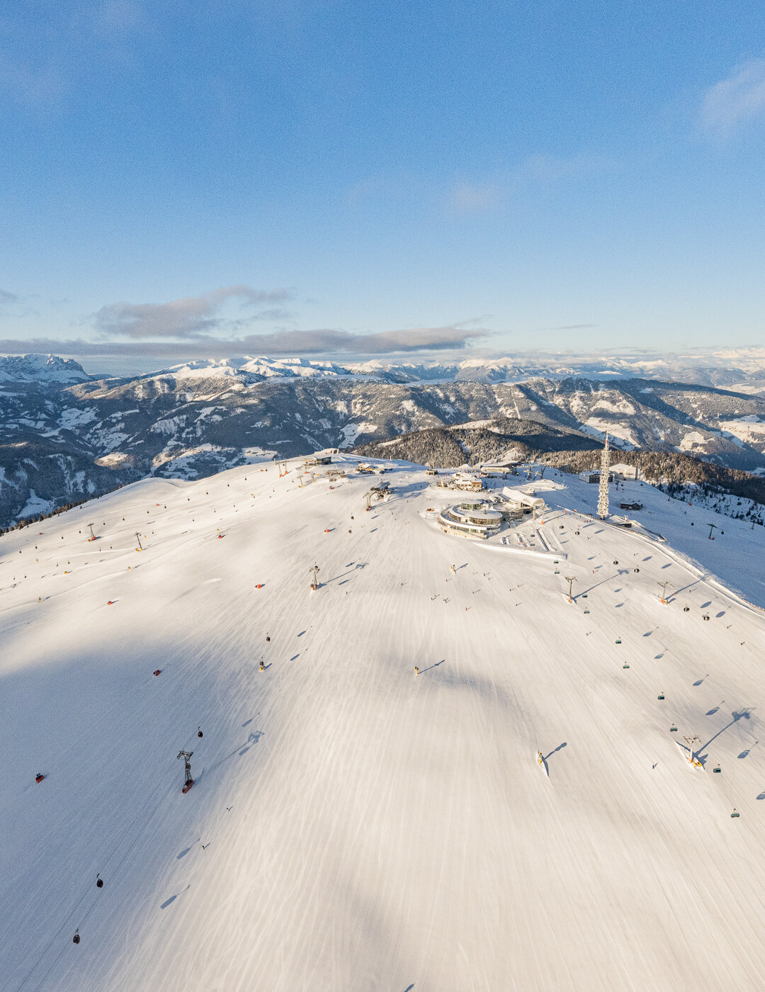 Panoramaaufnahme eines sonnigen Skibergs mit Blick über das Tal und umliegende Berglandschaft. | © Harald Wisthaler